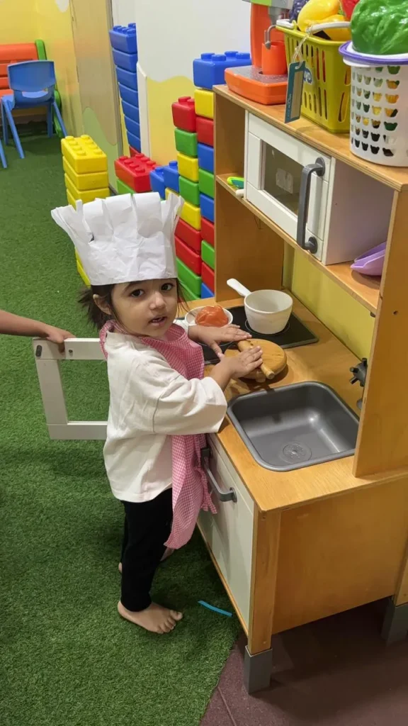 Child in chef cap at the pretend kitchen